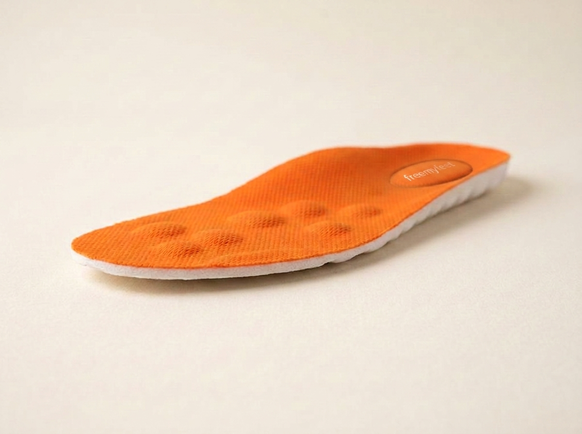 Oranje freemyfeet inlegzool van opzij, met de witte schuimlaag eronder en de noppen aan de bovenkant